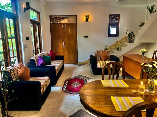 Una sala de estar con sofás y una mesa. en Jasmine villa - Mihiripenna, en Talpe