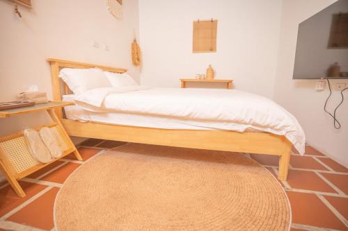a bedroom with a bed with white sheets and a rug at Zhu Shan Xian Ting in Jincheng