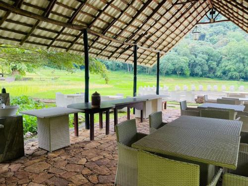 a patio with tables and chairs with a view of a field at Clio Ella Adventure in Ella