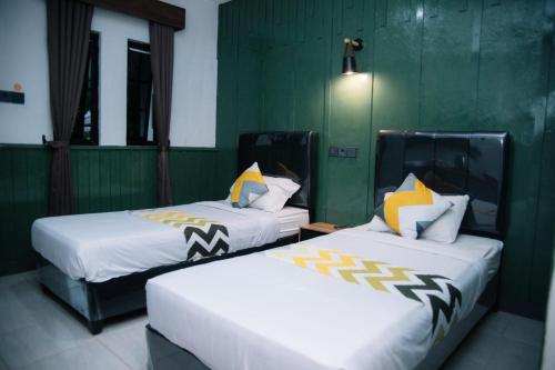 two beds sitting next to each other in a room at Handayani Hotel in Sumedang Utara