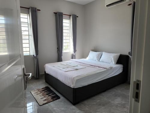 a bedroom with a bed with white sheets and two windows at 4 Bedroom Private Villa & Swimming Pool with Fitness in Phumĭ Thnŭng