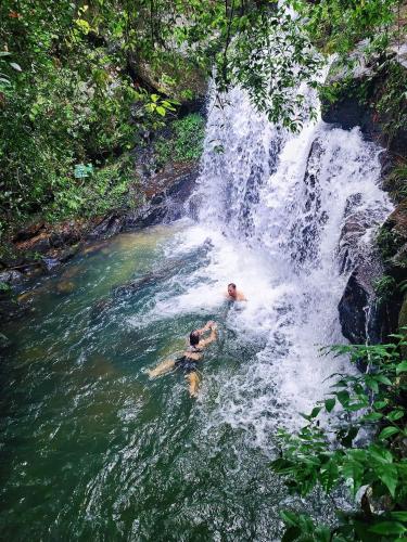 a couple of people swimming in a waterfall at Little Rock Homestay in Phong Nha