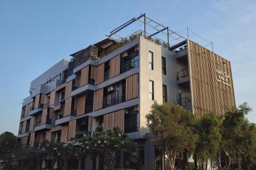 a tall building with trees in front of it at Amphawa Nanon Hotel in Amphawa