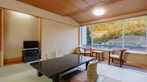 a dining room with a table and chairs and a large window at KAMENOI HOTEL Akita Yuze in Kazuno
