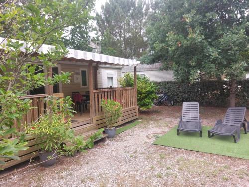 une cabine avec deux chaises et une terrasse couverte avec un patio dans l'établissement Mobil home 8 personnes 3 chambres, à Saint-Julien-en-Born