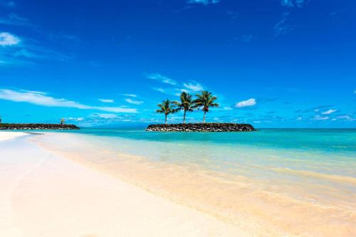 a beach with palm trees in the water at Sheraton Samoa Beach Resort in Mulifanua