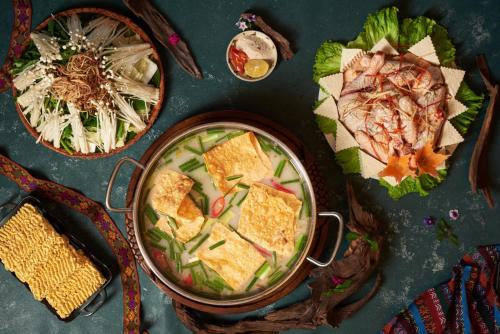 a table topped with a pot of food and plates of food at Mai Chau Hideaway Lake Resort in Mai Chau