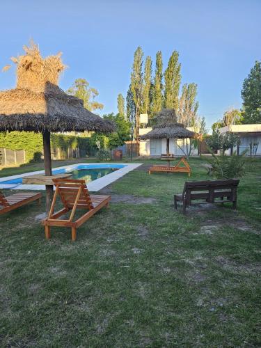 a pool with a picnic table and a straw umbrella at Complejo de Cabaña con pileta CABLE A TIERRA Cabaña Blend in San Rafael