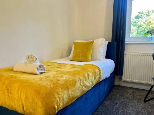 ein Schlafzimmer mit einem Bett mit gelben Laken und einem Fenster in der Unterkunft Long Stay 3br Parking Wifi in Corby