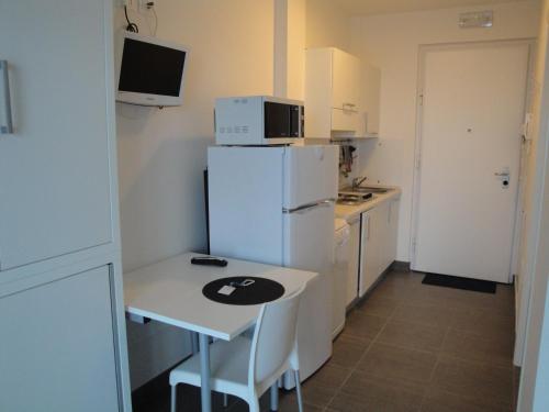 a small kitchen with a table and a refrigerator at Residence La Nave in Senigallia
