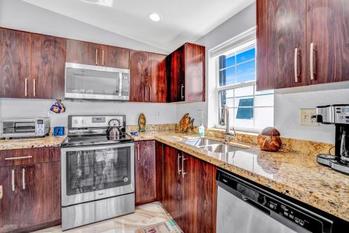 a kitchen with wooden cabinets and stainless steel appliances at Tiki Time! Pool-tiki Hut-kayaks-grill-ocean View! in Marathon