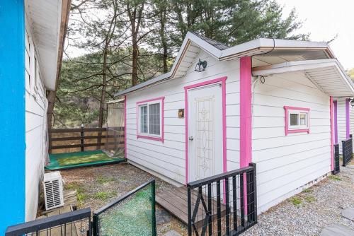 a pink and white tiny house with a porch at Gapyeong Cherrish Pension in Kwanch'ŏng-ni