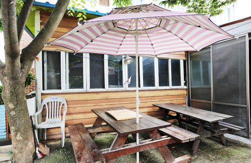 a picnic table with an umbrella in front of a house at Taean Gaetyeowool Pension in Taean