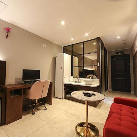 a living room with a red couch and a desk at Browndot Hotel Godeok newtown in Pyeongtaek