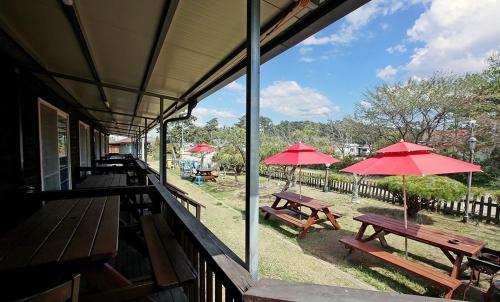 a group of picnic tables with red umbrellas on a building at Mongsanpo Dream House in Taean