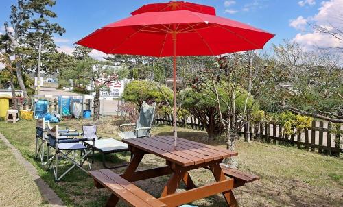 a picnic table with a red umbrella and chairs at Mongsanpo Dream House in Taean