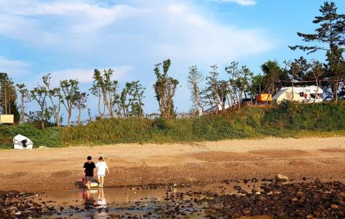 two people walking on the shore of a beach at Padowa Noeul Camping in Mokōri
