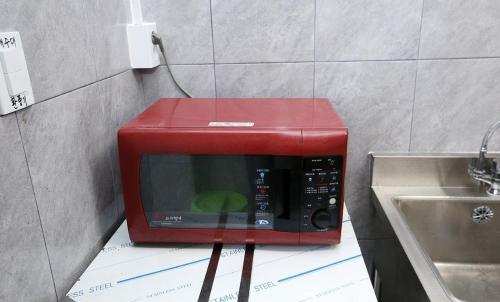 a red microwave sitting on a counter next to a sink at Padowa Noeul Camping in Mokōri