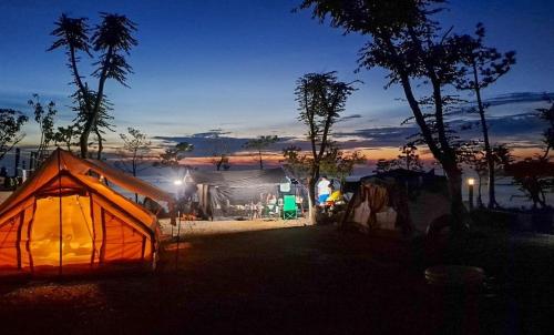 a tent is lit up at night near a lake at Padowa Noeul Camping in Mokōri