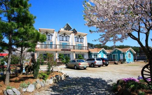 a large house with cars parked in a parking lot at Silver Glowing Sea Pension in Taean