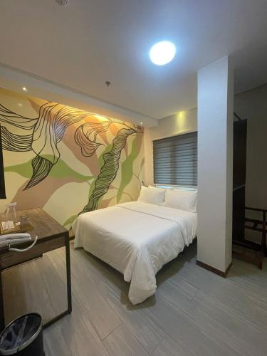 a bedroom with a bed with a painting on the wall at Maharlika City Inn in Bacolod