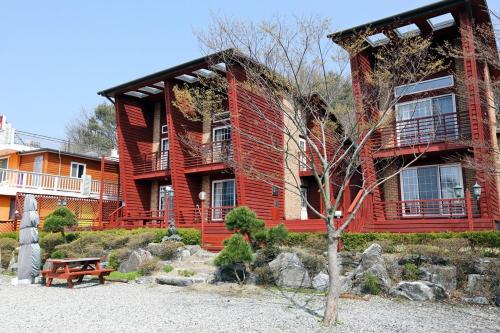 a large red house with a bench in front of it at Milart Pension in Taean