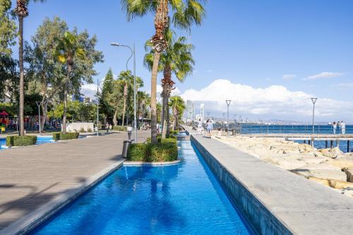 a swimming pool next to a beach with palm trees at 74 Prokymea- Steps from the Sea, Downtown, Balcony in Limassol