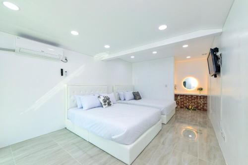 a white bedroom with a white bed and a television at Sellin Onsu Swimming Pool Pension in Gapyeong