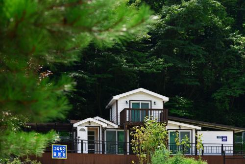 a white house with a balcony and trees at Gapyeong Gratia glamping in Gapyeong