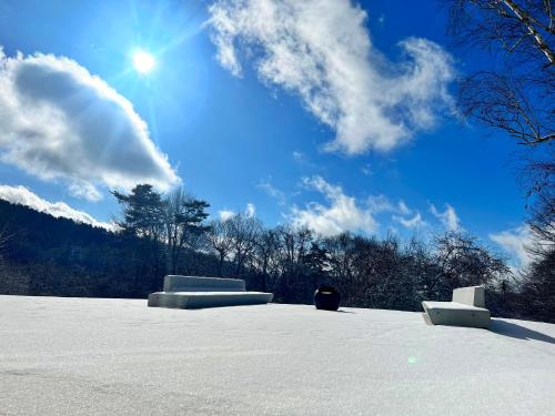 a snow covered field with the sun in the sky at HOTEL de L'ALPAGE in Chino