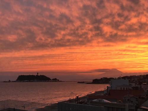 a sunset over a body of water with a city at 湘南OCEAN HOUSE in Koshigoe