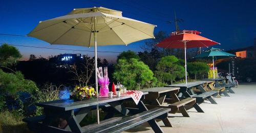 a row of picnic tables with umbrellas at night at Buan Badatgaeui Chuoek Pension in Buan