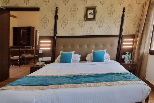 a bedroom with a large bed with blue pillows at Labh Garh Palace Resort & Spa in Udaipur