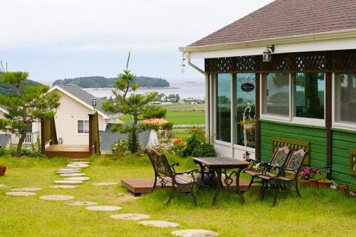 a house with a table and chairs in the yard at Pension on the Sea Shore in the Bosom Department Byeonsanbando in Buan