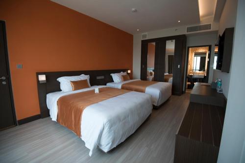 two beds in a hotel room with orange walls at Astana Wing - Riverside Majestic Hotel in Kuching