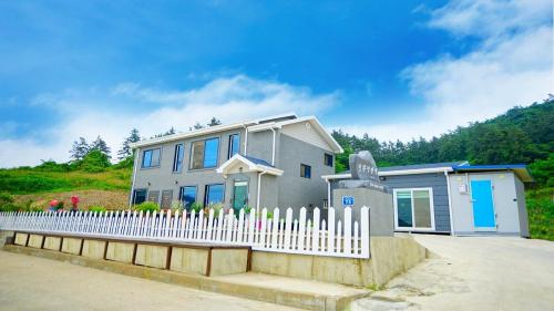 a small house with a white picket fence at wido cinhwangyeongpensyeon in Buan