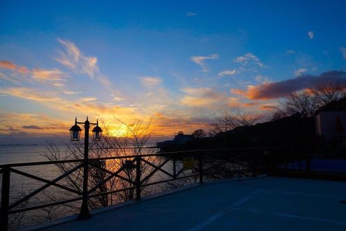 a sunset over the water with a fence and a street light at Byeonsanbando Badajeonmangdae Pension in Buan