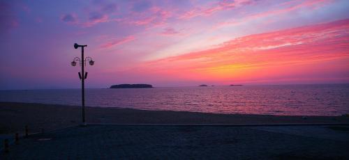 a sunset over the ocean with a street light on the beach at Buan Floor Pension in Buan