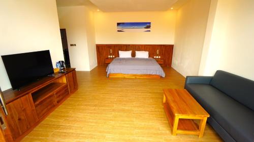 a bedroom with a bed and a tv and a couch at BAGUS Guest House in Legian