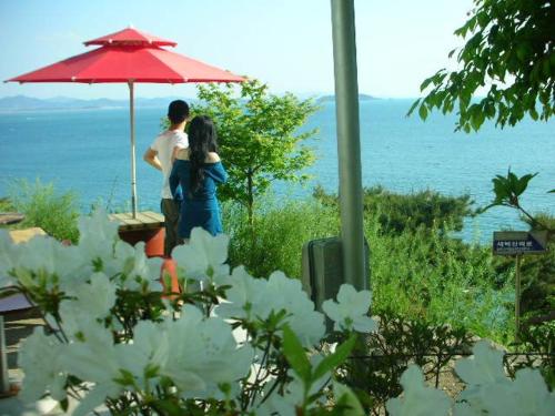 two people standing under an umbrella near the water at Buan Jeonmang Joeun Pension in Buan