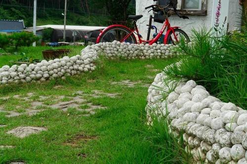 a red bike parked next to a rock wall at Buan Bbalgan Jibung Pension in Buan