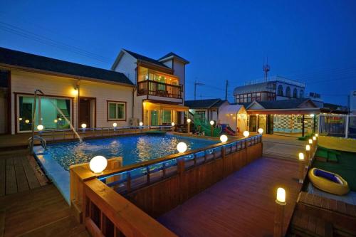 a swimming pool with lights on a wooden deck at anmyeondo neipkeulrobeo suyeongjangpensyeon in Chŏkkae