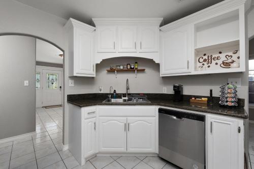 a kitchen with white cabinets and a sink at Modern rustic home in Olmito