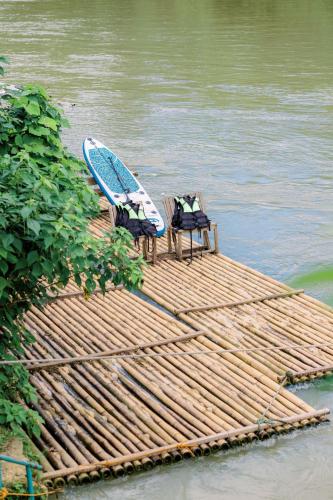 two chairs and a surfboard on a dock in the water at Busai Dream Falls Resort in Loboc