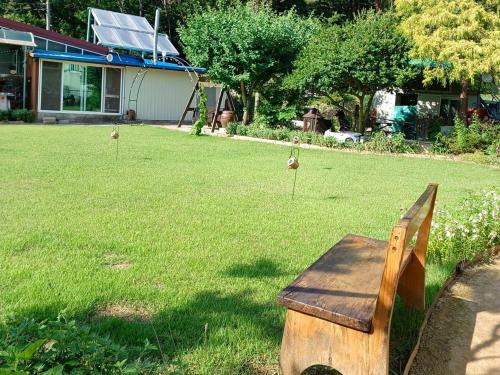 a wooden bench sitting in a yard with birds in the grass at Private pension Jeongwonchae in Wanju