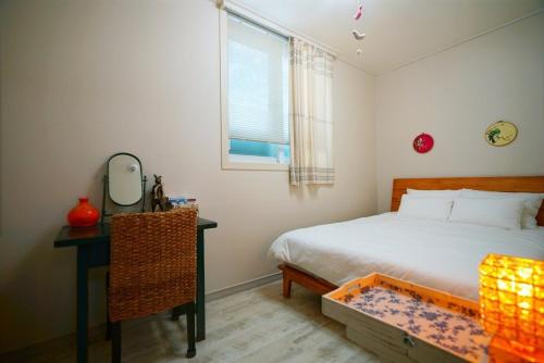 a bedroom with a bed and a desk and a window at Jeonju Hanok Village Dohwaseoga Stay Private Pension in Jeonju