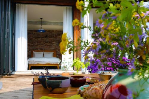 a porch with flowers and a bed in the window at Jeonju Hanok Village Dohwaseoga Stay Private Pension in Jeonju