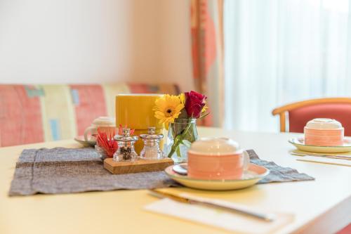 a table with plates and a vase of flowers on it at Leitner Gästehaus in Scheifling