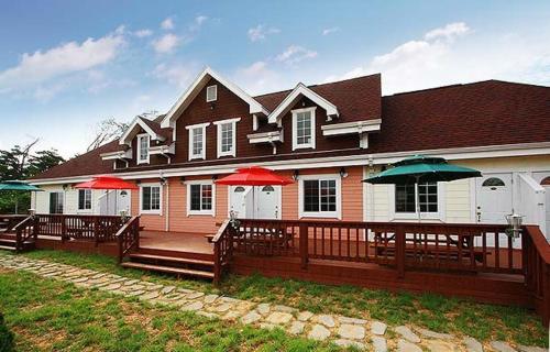 a house with red and green umbrellas on a deck at Namdangrodem Pension in Hwangdo