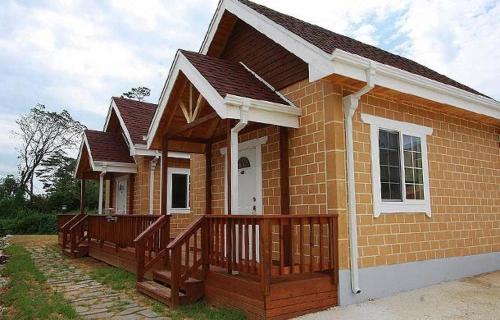 a small brick house with a wooden deck at Namdangrodem Pension in Hwangdo